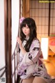 A woman in a kimono sitting on a window sill.