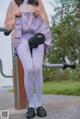 A woman in a pink shirt and white tights holding a pair of dumbbells.